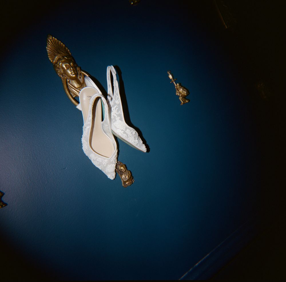 White bridal shoes with golden ornaments against a dark blue background.