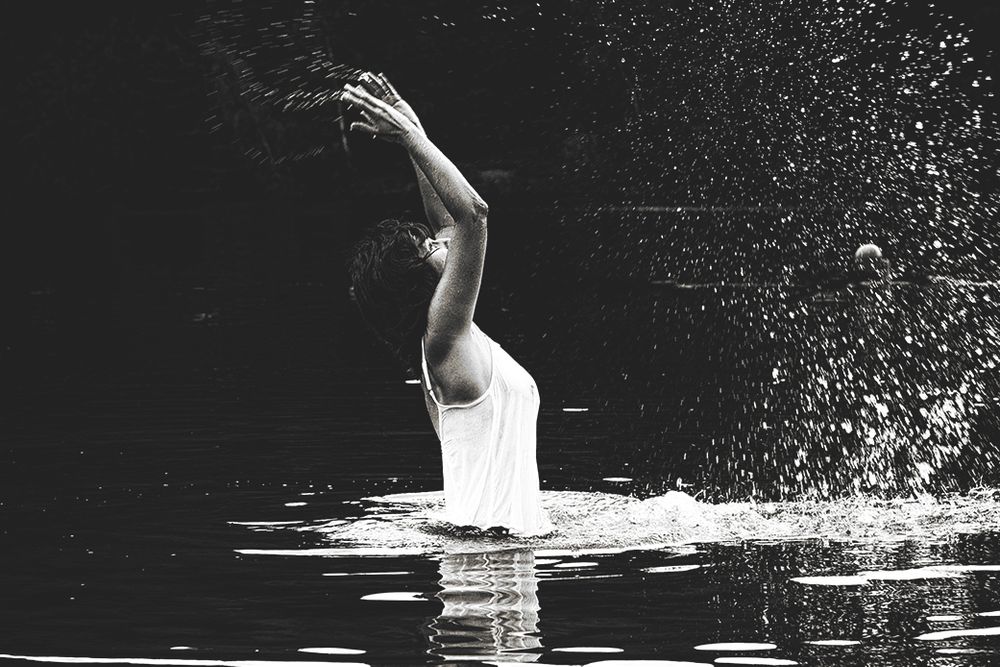 Spiel mit Licht und Schatten im See mit Wassertropfen und einer Frau in weißem Oberteil