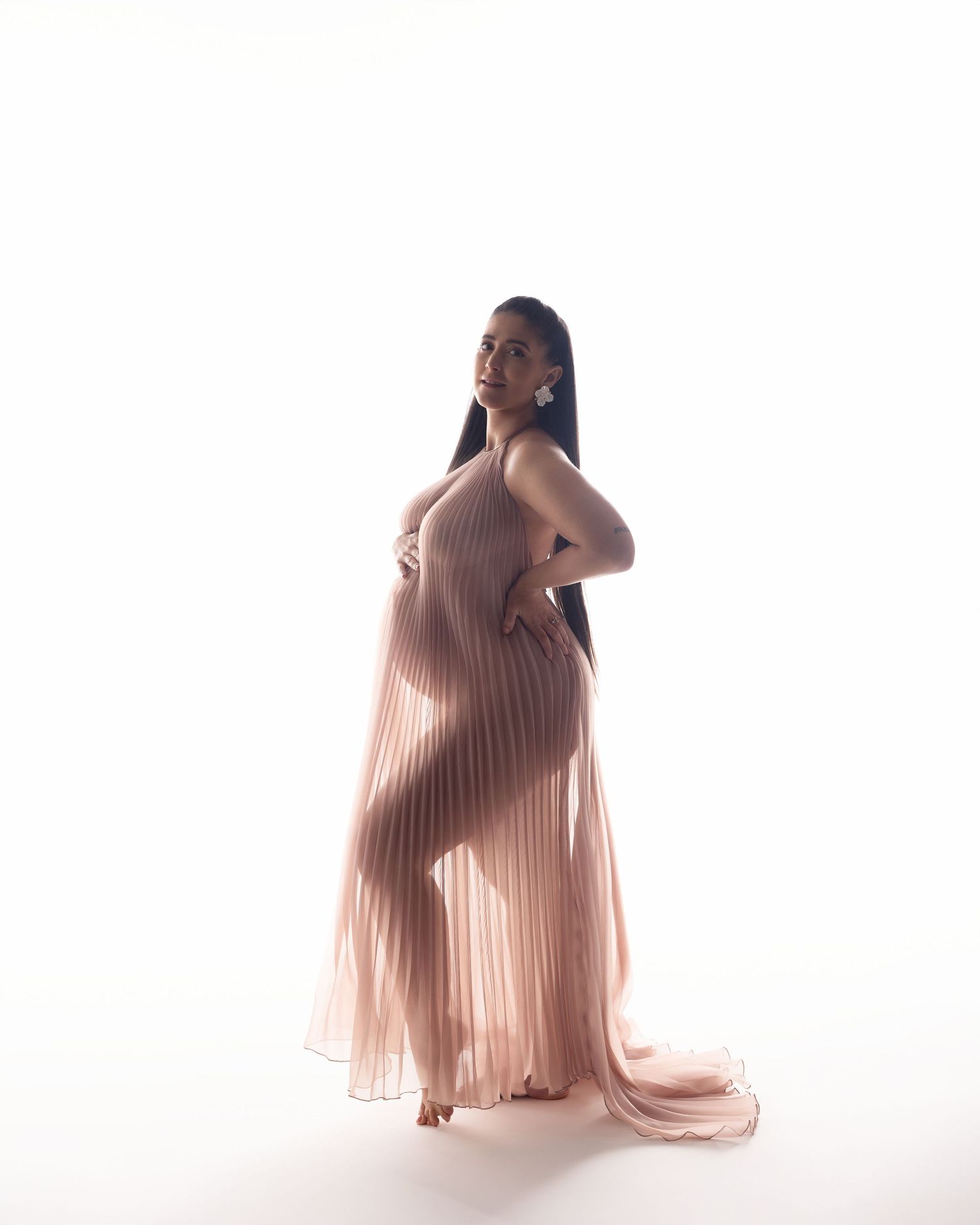 A person in a flowing pink pleated dress poses gracefully in three different positions against a white backdrop.
