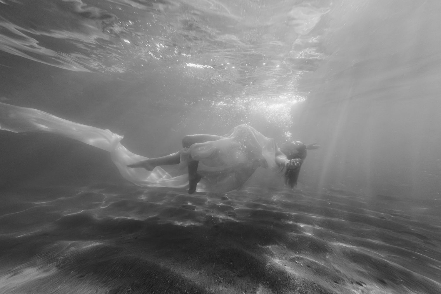 An underwater maternity photography session in black and white captured in the ocean in Point Samson