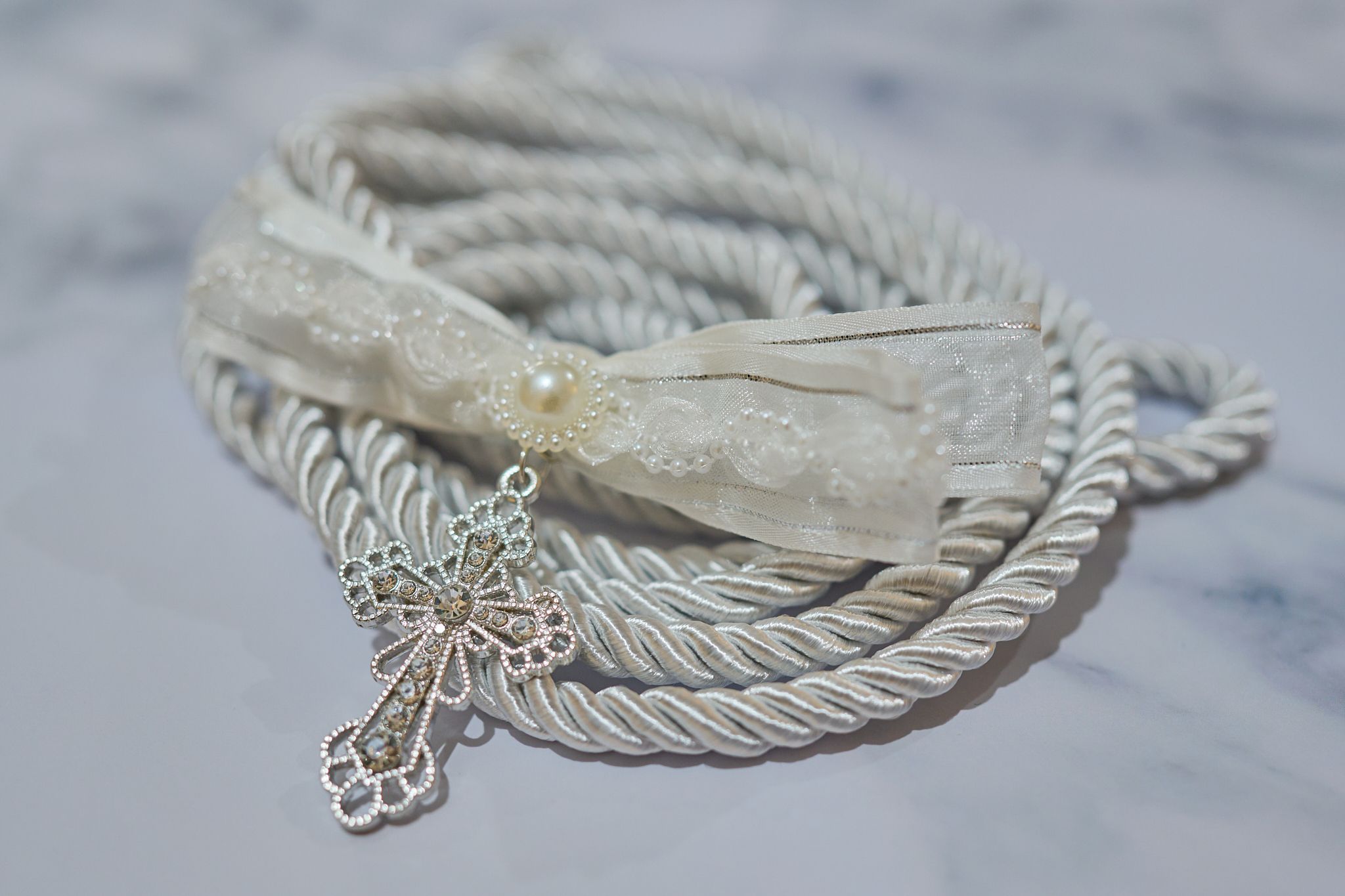 A cross with rope and ribbon on a marble surface.