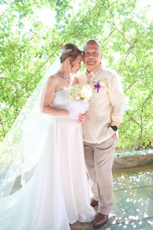 Couple shares a tender moment under green spring foliage at St. Bernadette's Catholic Church in Stockton California.
