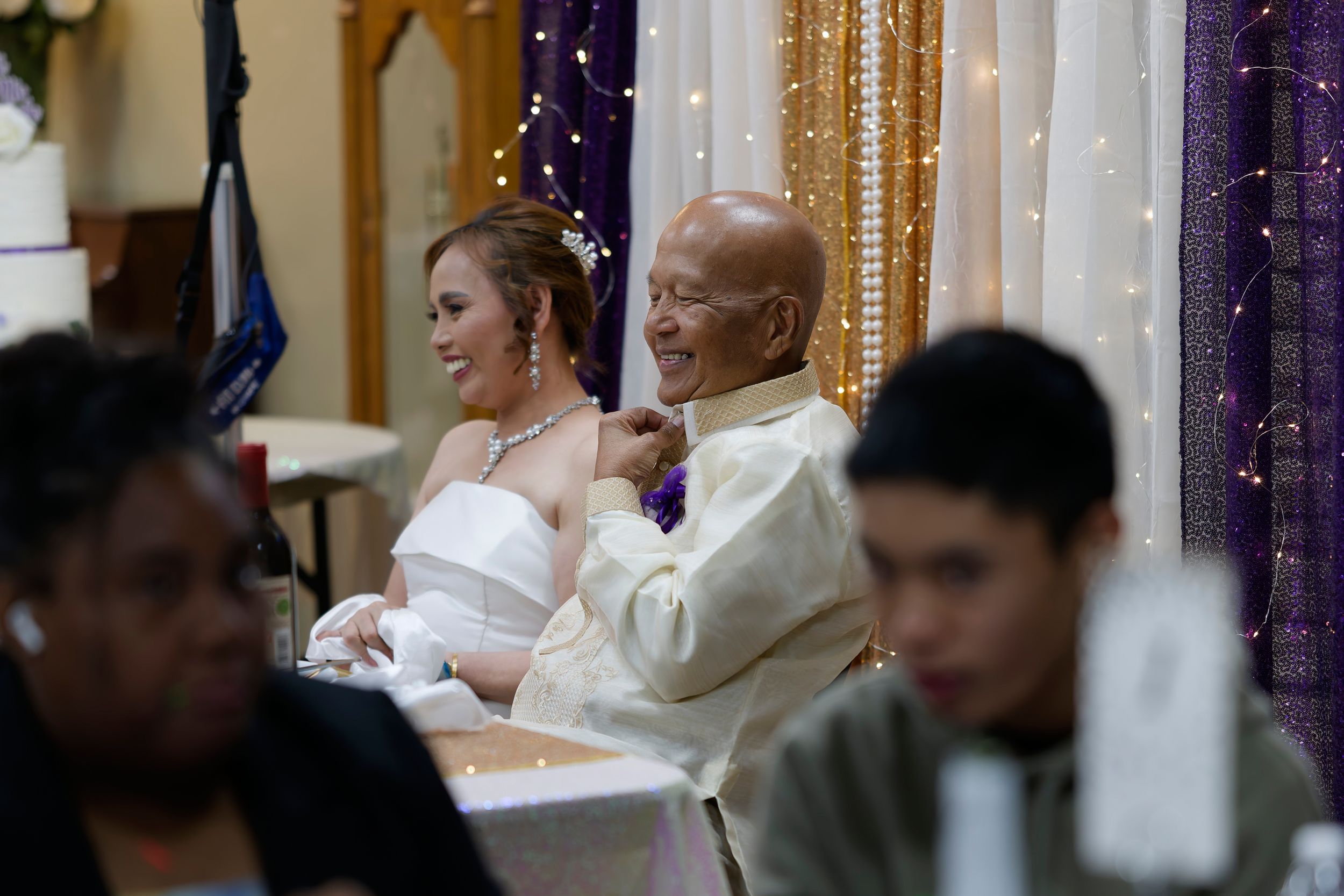 A couple sits together at an elegantly decorated wedding reception at St. Bernadette's Catholic Church in Stockton California.