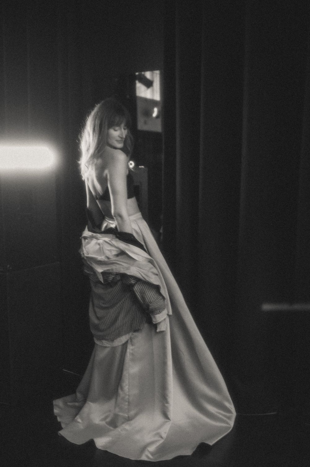 Dramatic black and white photo of swirling white dress movement in dark theater space.