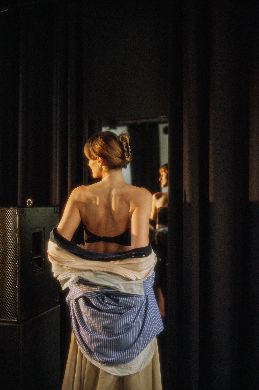 Artistic performance showing bare shoulders and striped fabric in moody lighting.
