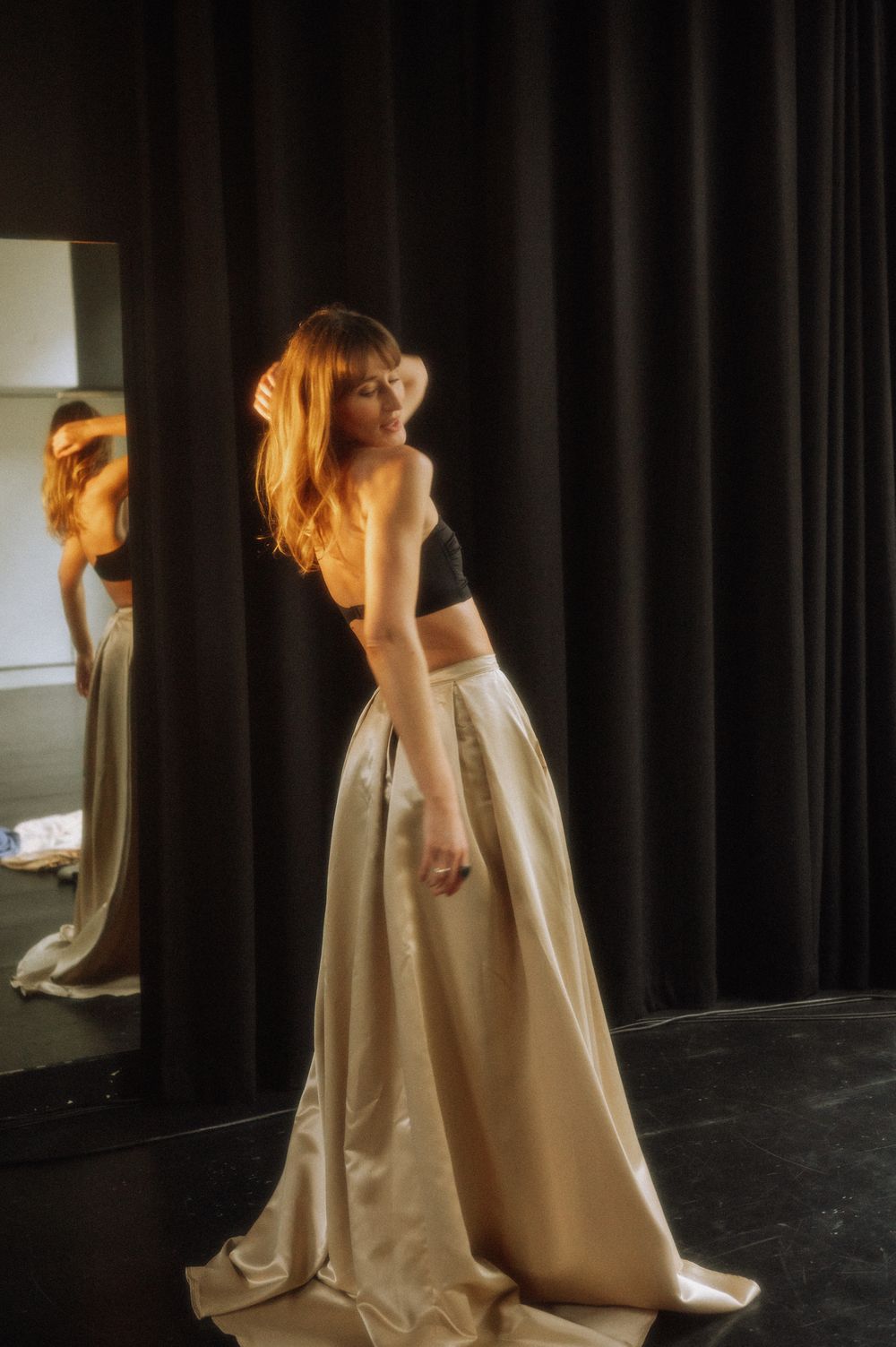 Ethereal dance performance with cream colored dress against dark curtained backdrop.