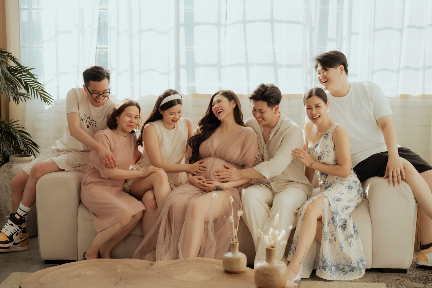 Group lounging together on beige couch in bright sunlit room with casual atmosphere.