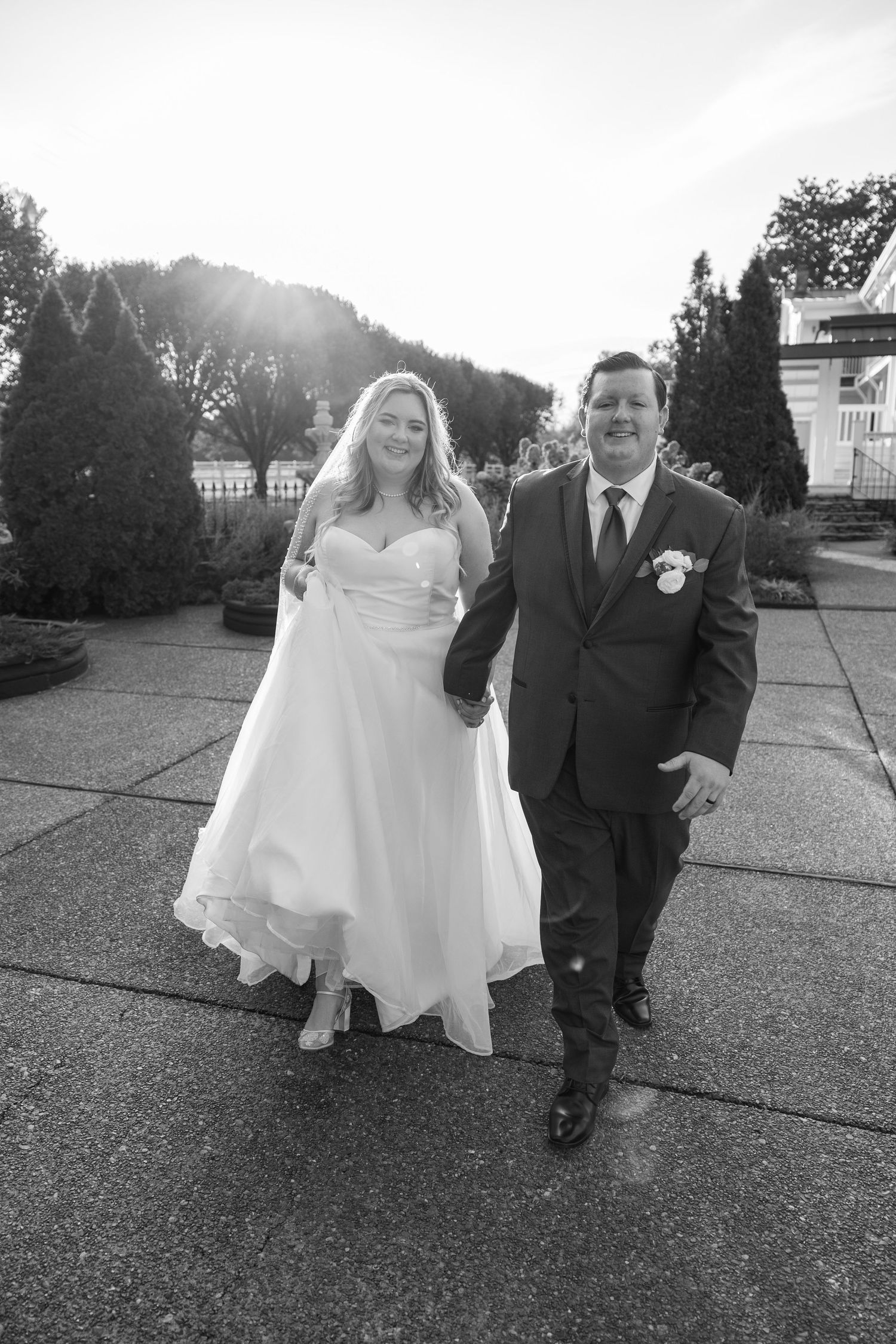 A bride and groom walk together on a paved outdoor path in black and white photography at Nashville, TN wedding venue.