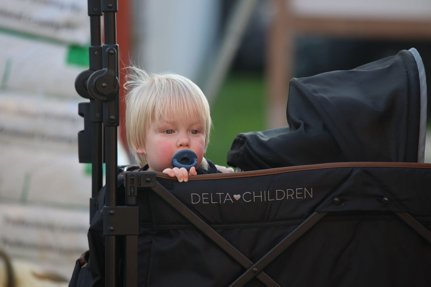 Small child sitting in black Delta Children wagon.