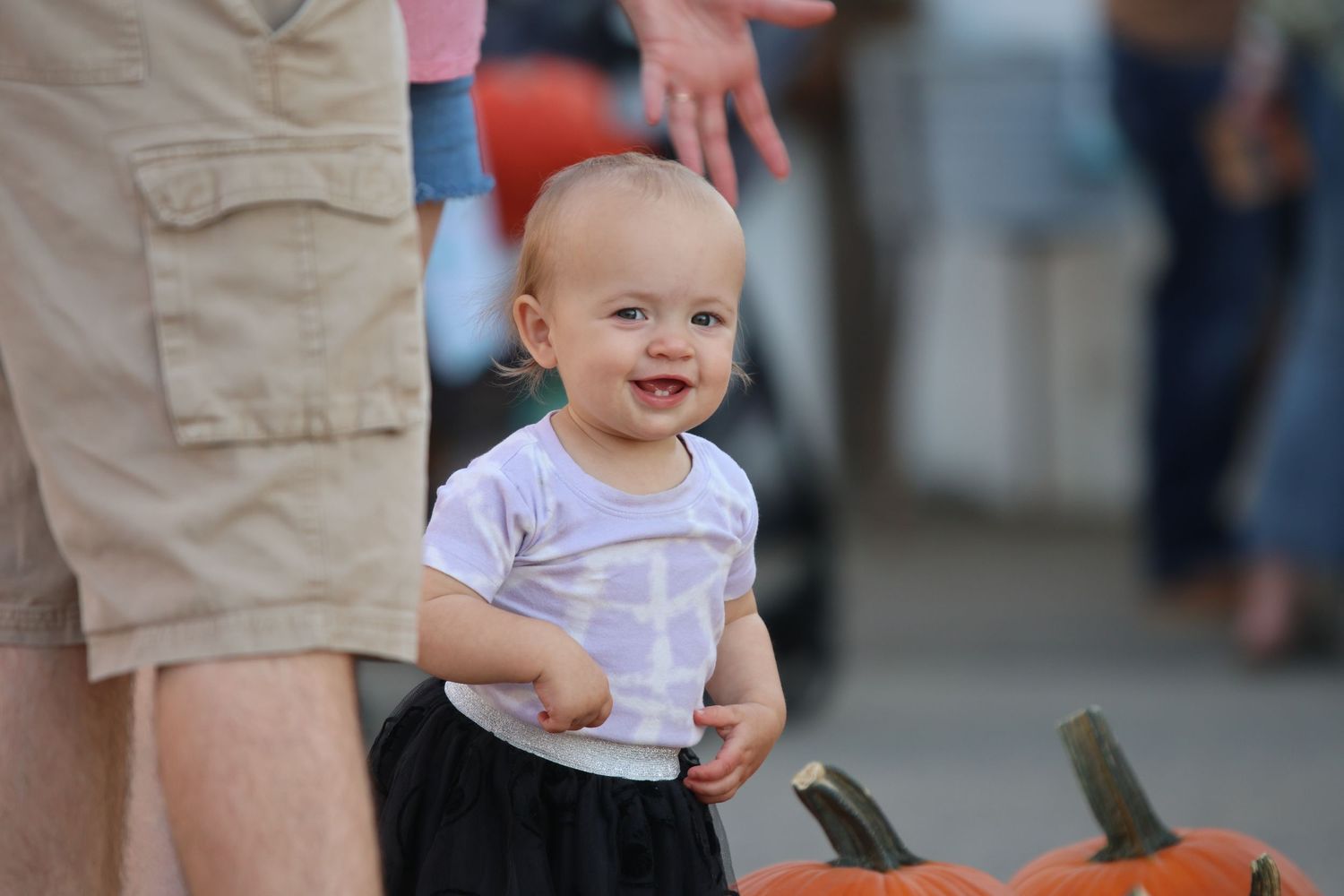 Happy child in white shirt near pumpkin display.