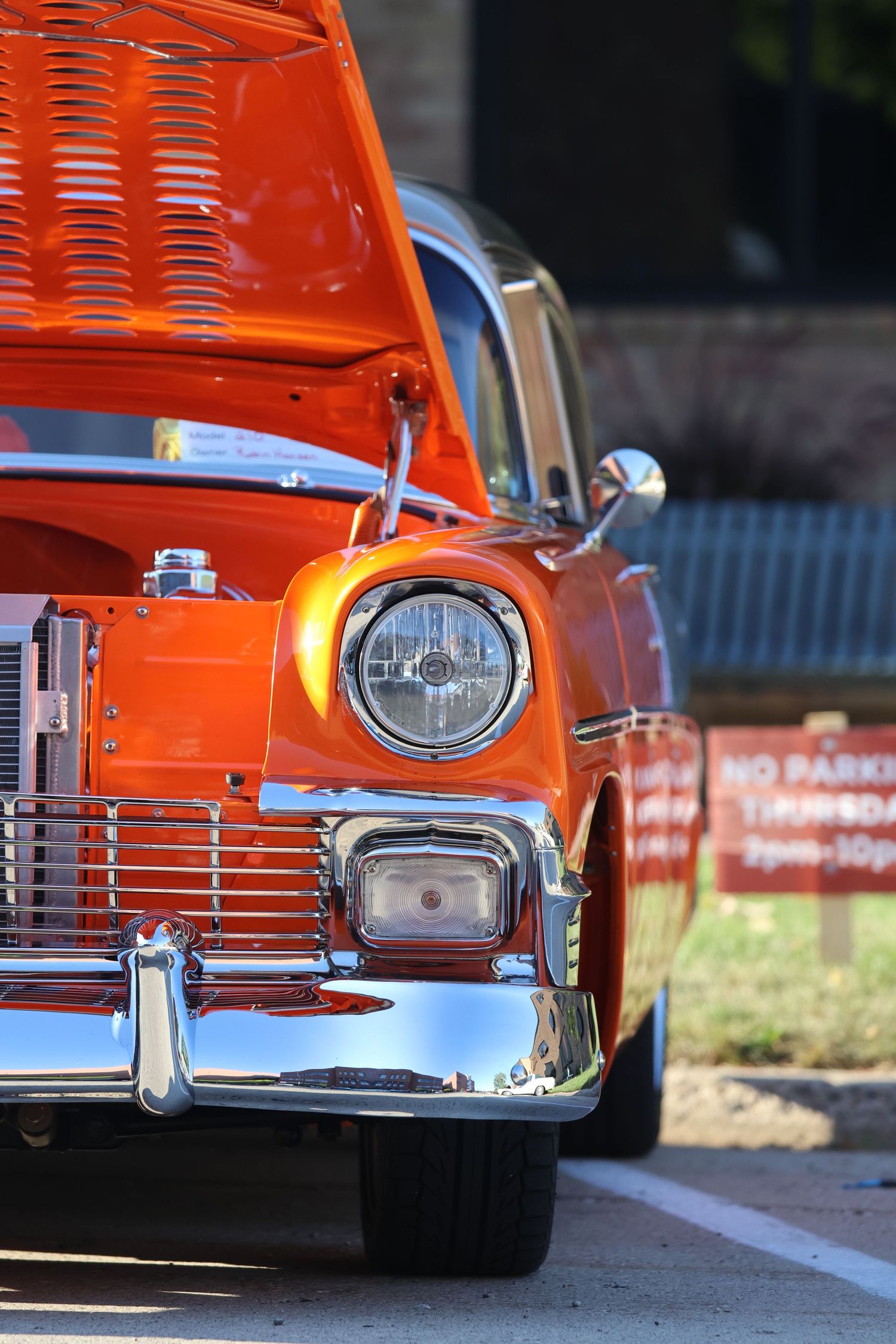 Front view of a classic orange Chevrolet with chrome trim and headlight detail.