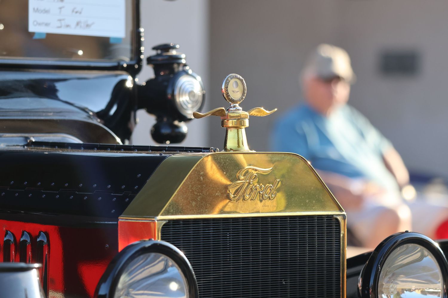 Vintage Model T Ford hood ornament and radiator grille in golden finish.