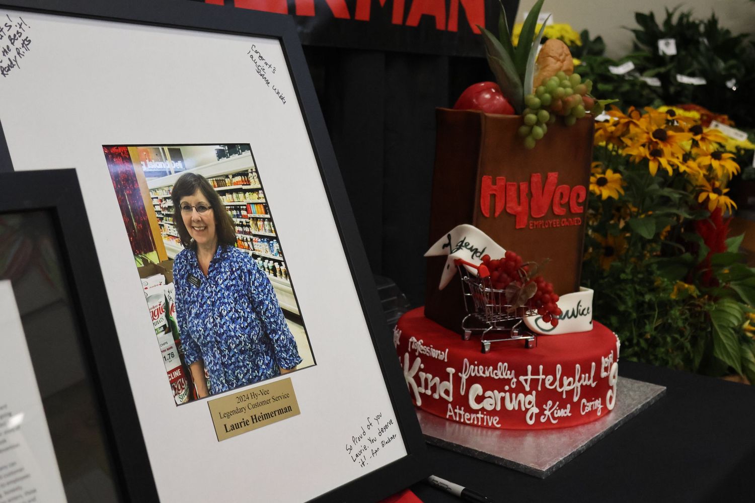 Display showing framed photo and decorative cake with red text.