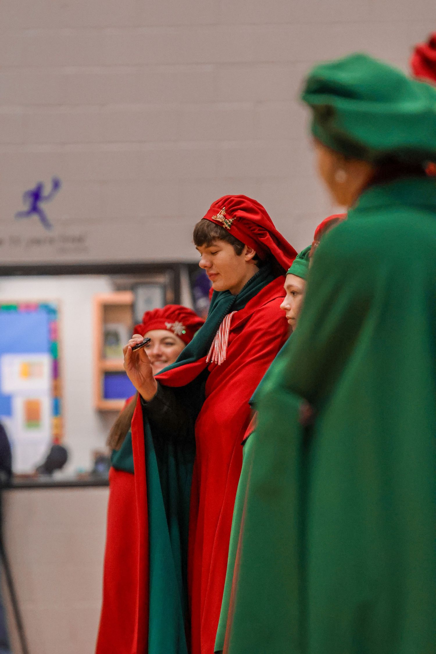Performers in red and green holiday costumes standing in formation.