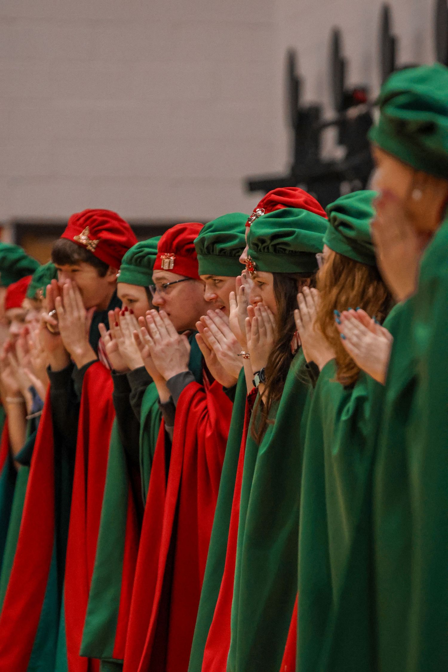 Performers in red and green holiday attire clapping in unison.