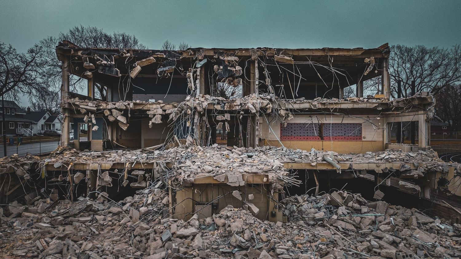 Demolished building with exposed structural elements against cloudy sky.