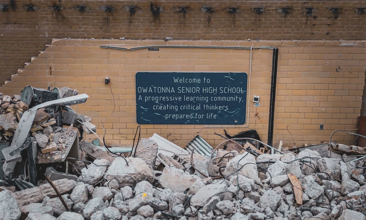 Rubble and debris from destroyed building with sign visible among the wreckage.