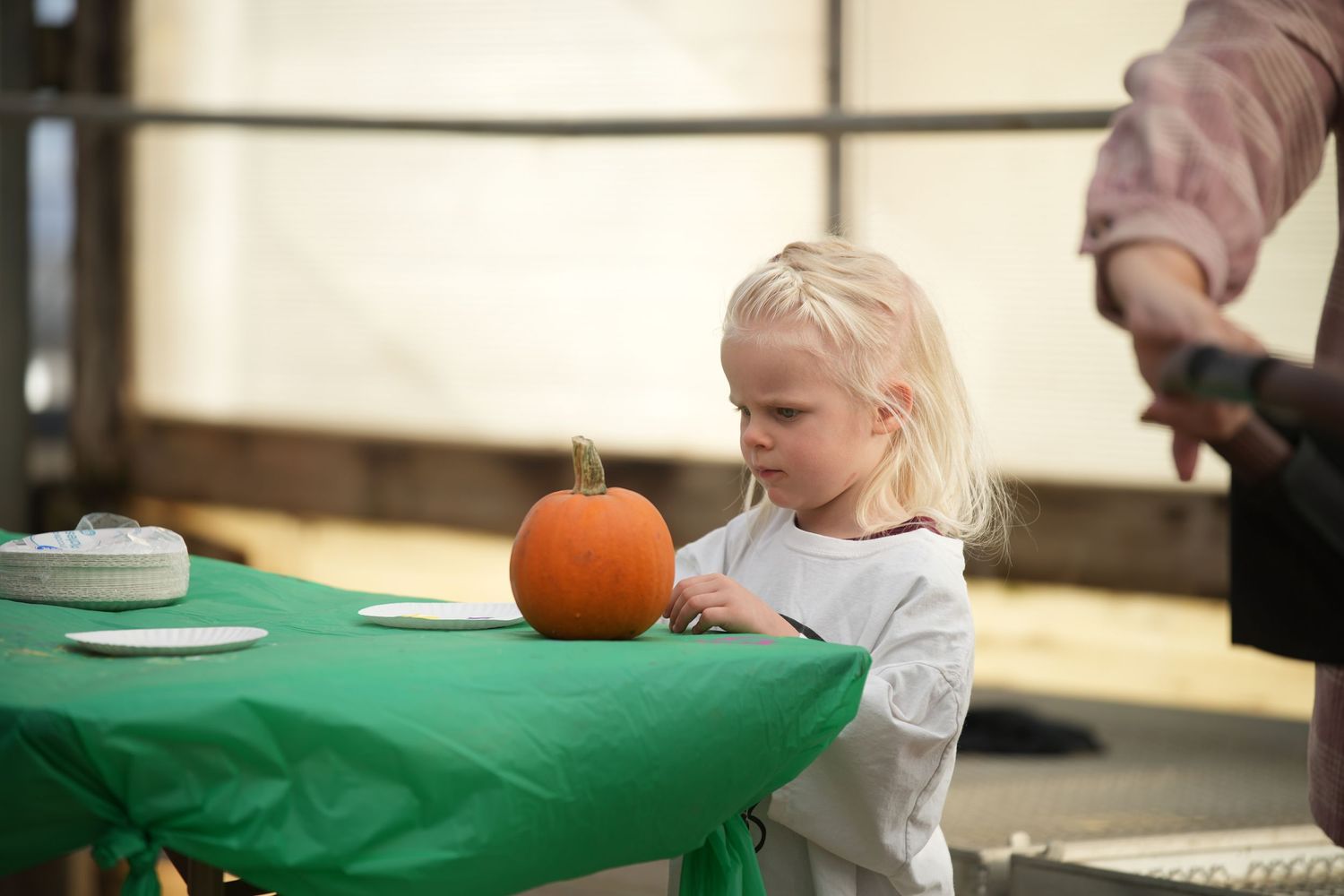 Kids participating in a pumpkin-themed activity at a table with green tablecloth.