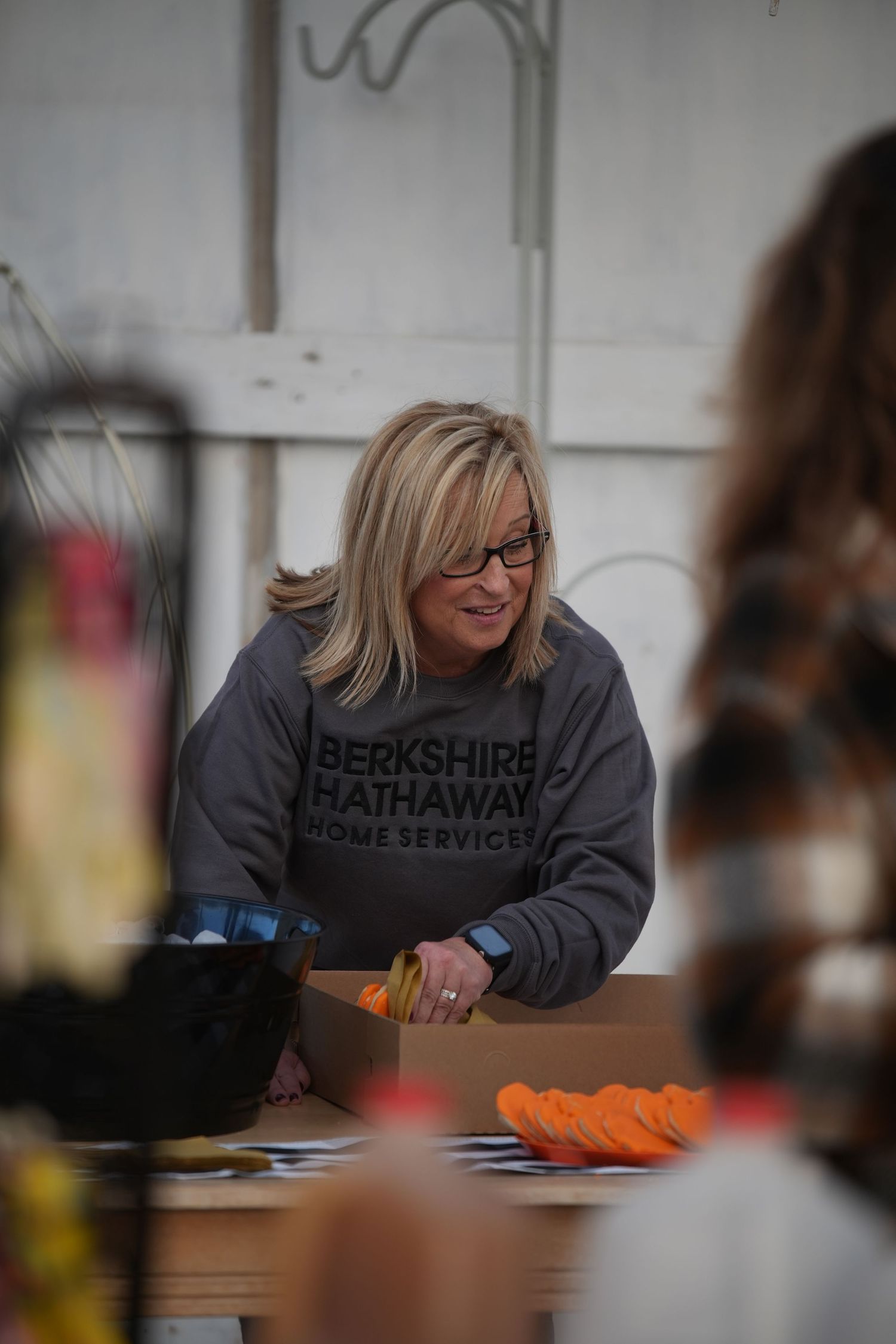 A person in a gray sweatshirt sits at a desk writing or studying in a classroom setting.