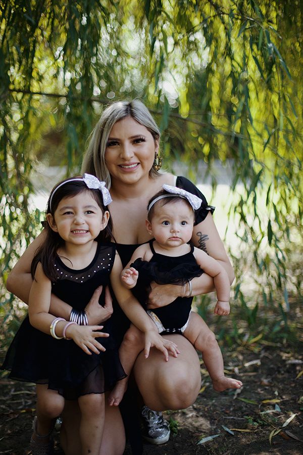 A mother holding her children under a tree.