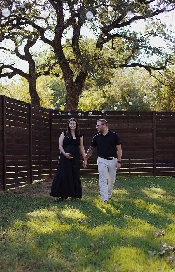 Couple holding hands and walking together on grass.