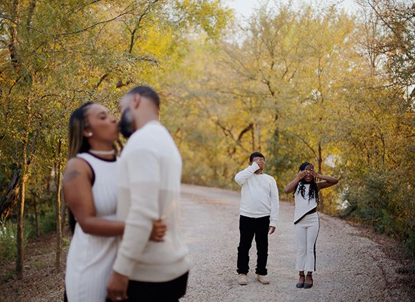 Parents kissing while the children cover their eyes.