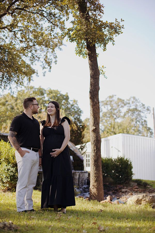 Pregnant couple staring at each other near a waterfall.