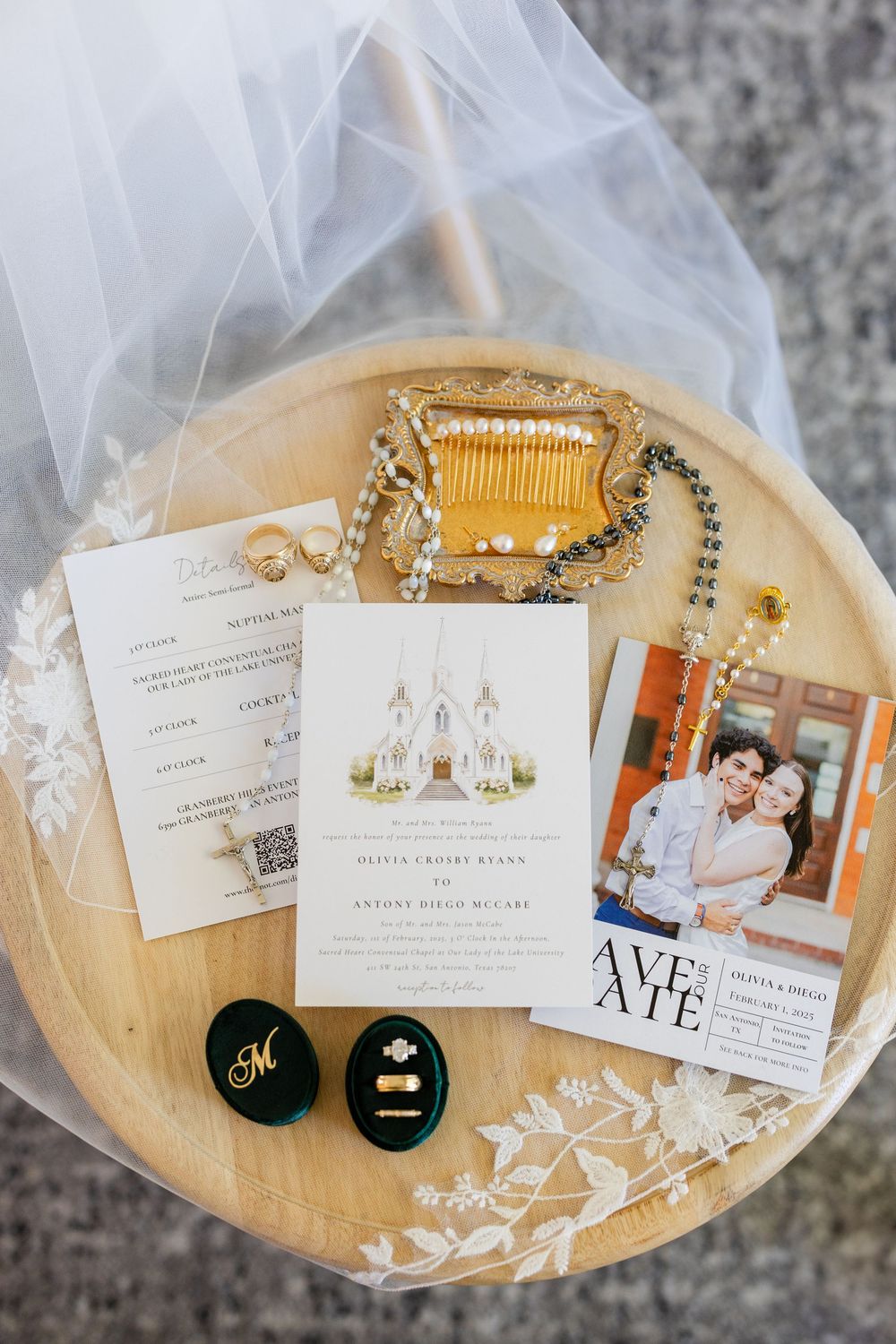 Wedding invitations, jewelry, and save-the-date cards arranged on a decorative wooden plate with tulle.