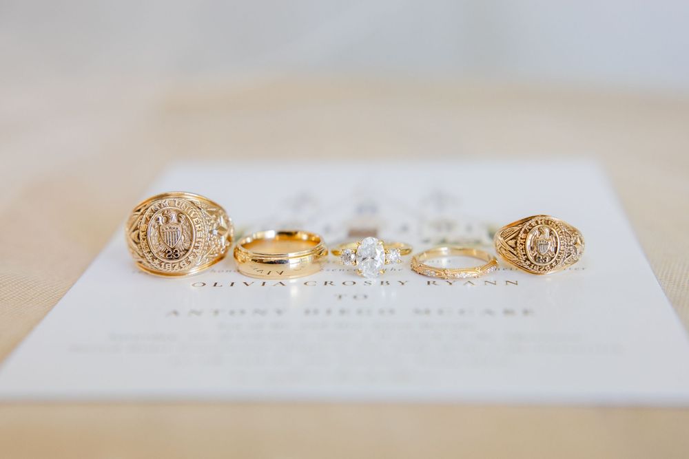 Gold monogram earrings and rings displayed on white textured surface with sparkly crystal details.