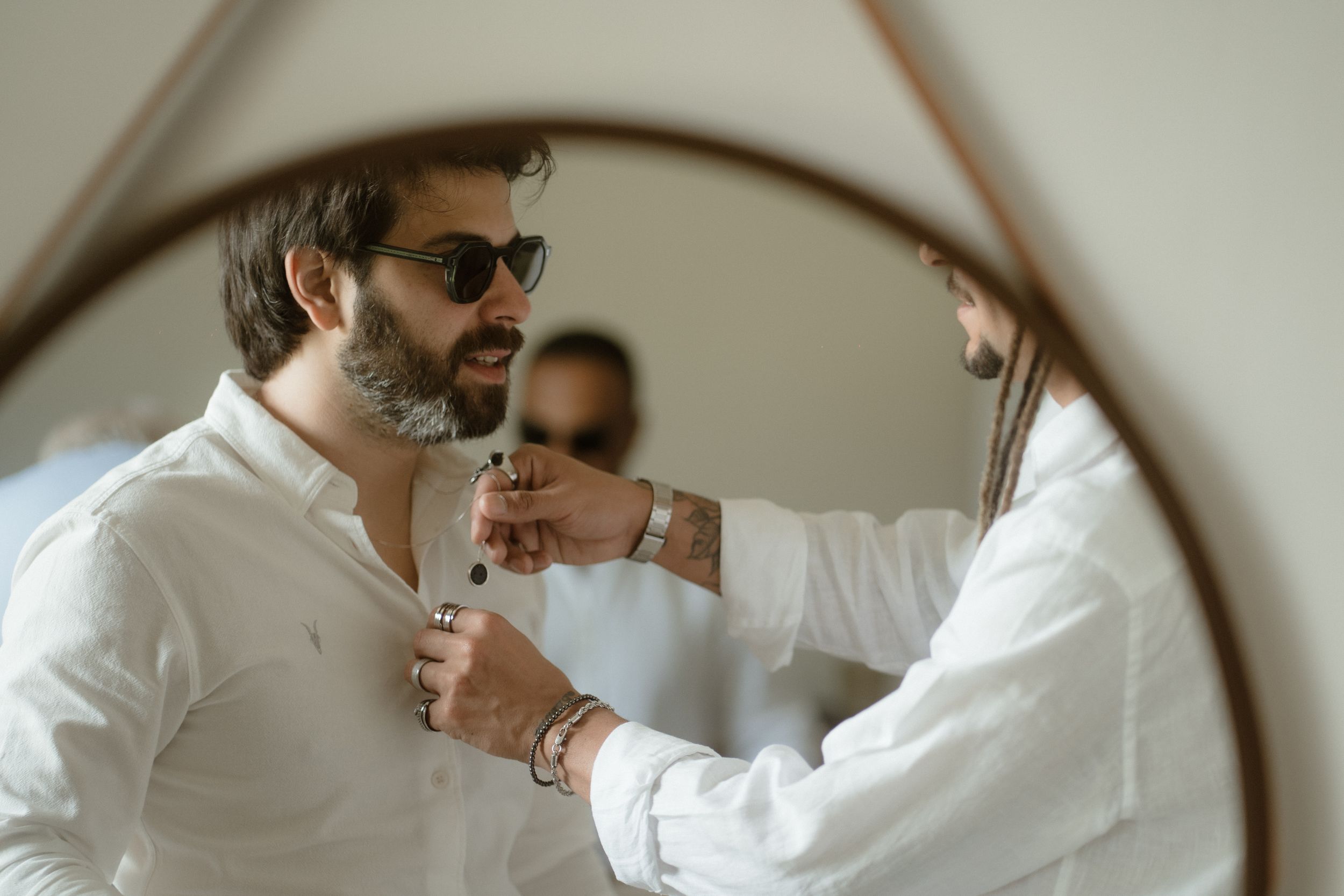A mirror reflection shows the final adjustments being made to a white formal shirt.