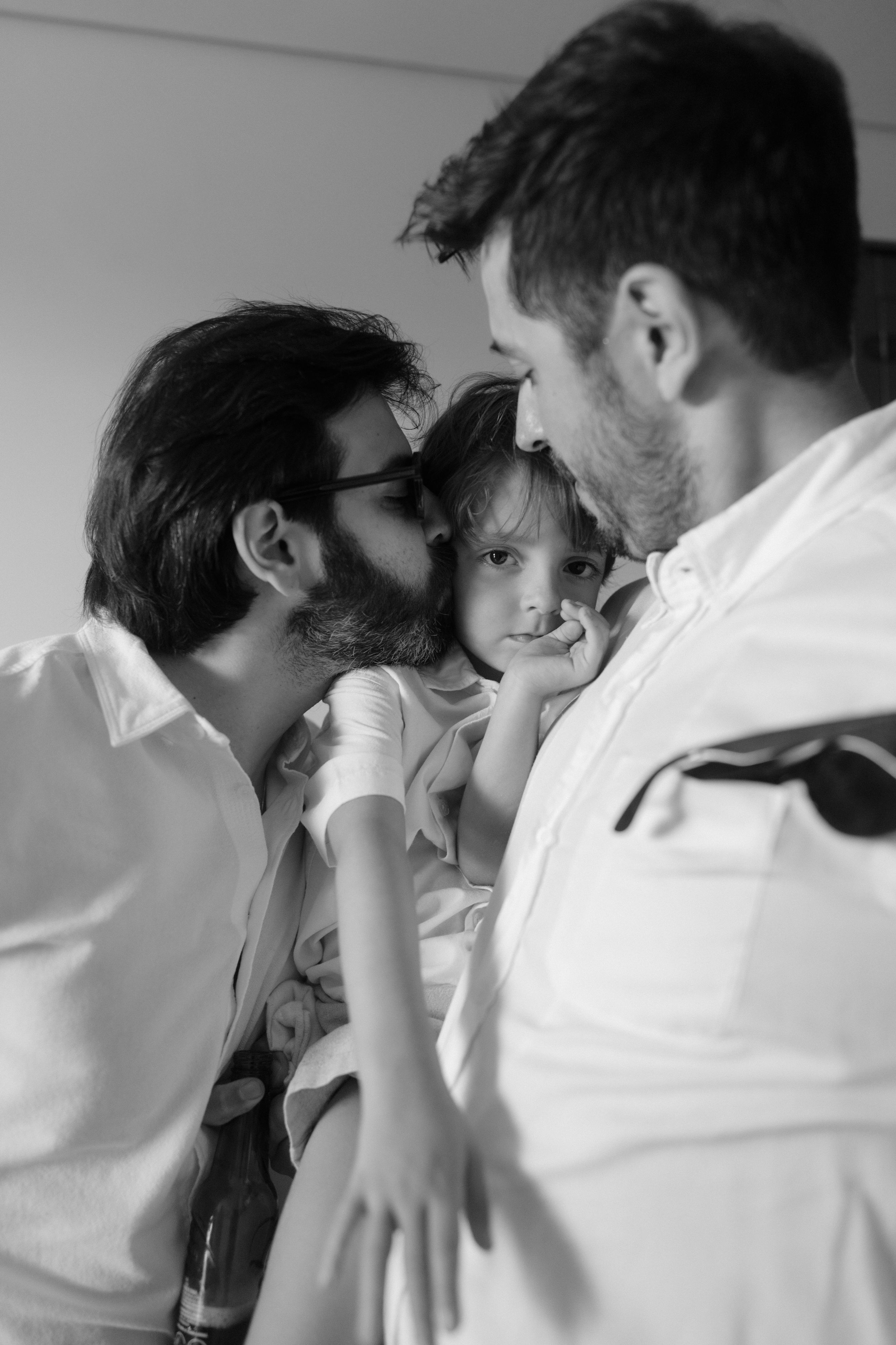 Three people share an intimate family moment together in a black and white photograph.