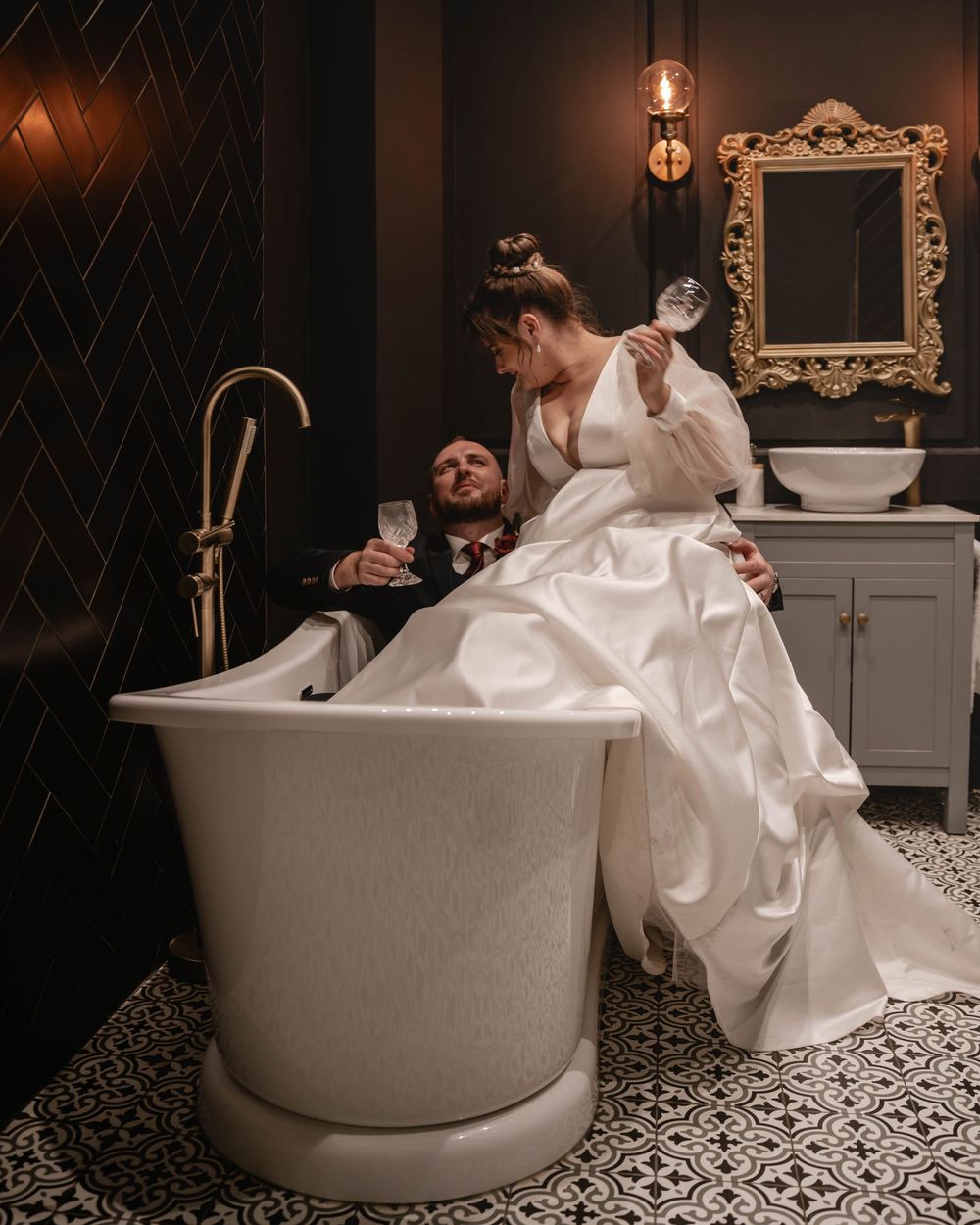 A romantic wedding photo captured in a luxurious bathroom with a freestanding tub and ornate decor.