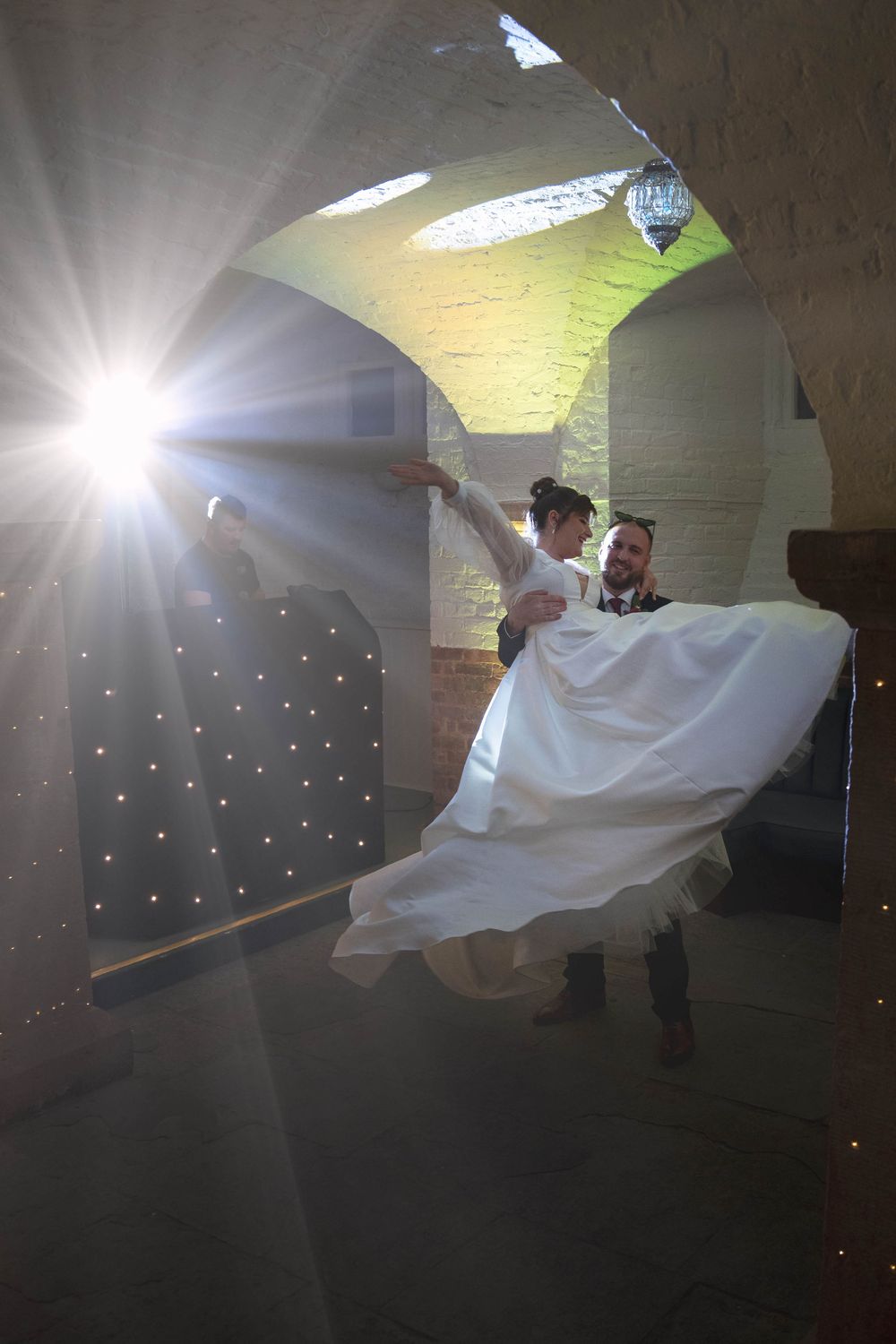 A dramatic backlit wedding dance captured in an arched venue with streaming sunlight.