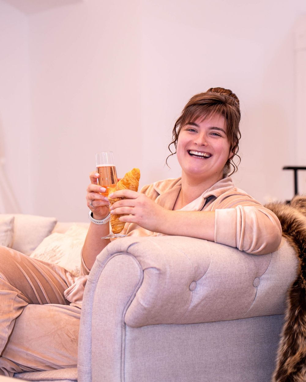 A relaxed guest enjoys a drink while sitting comfortably in a plush armchair at a celebration.