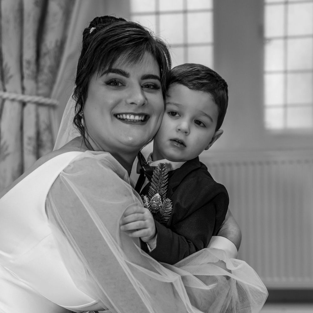 A tender moment between bride in white dress and young child at a wedding celebration.