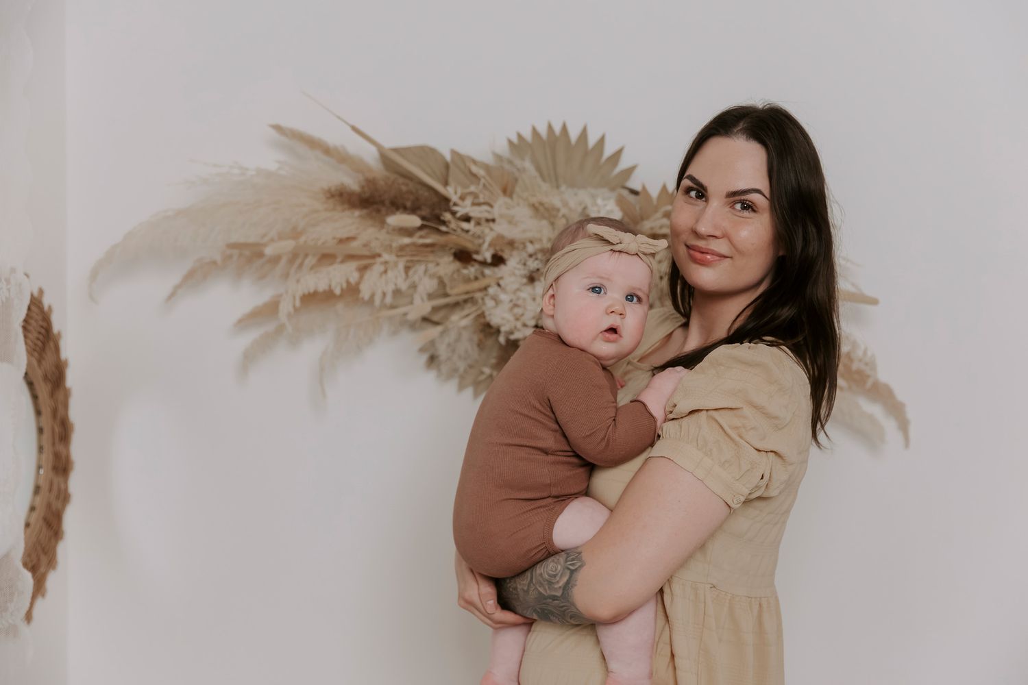 Livsstilsfoto af mor og baby i jordfarver foran en neutral baggrund. Børnefotograf Fyn