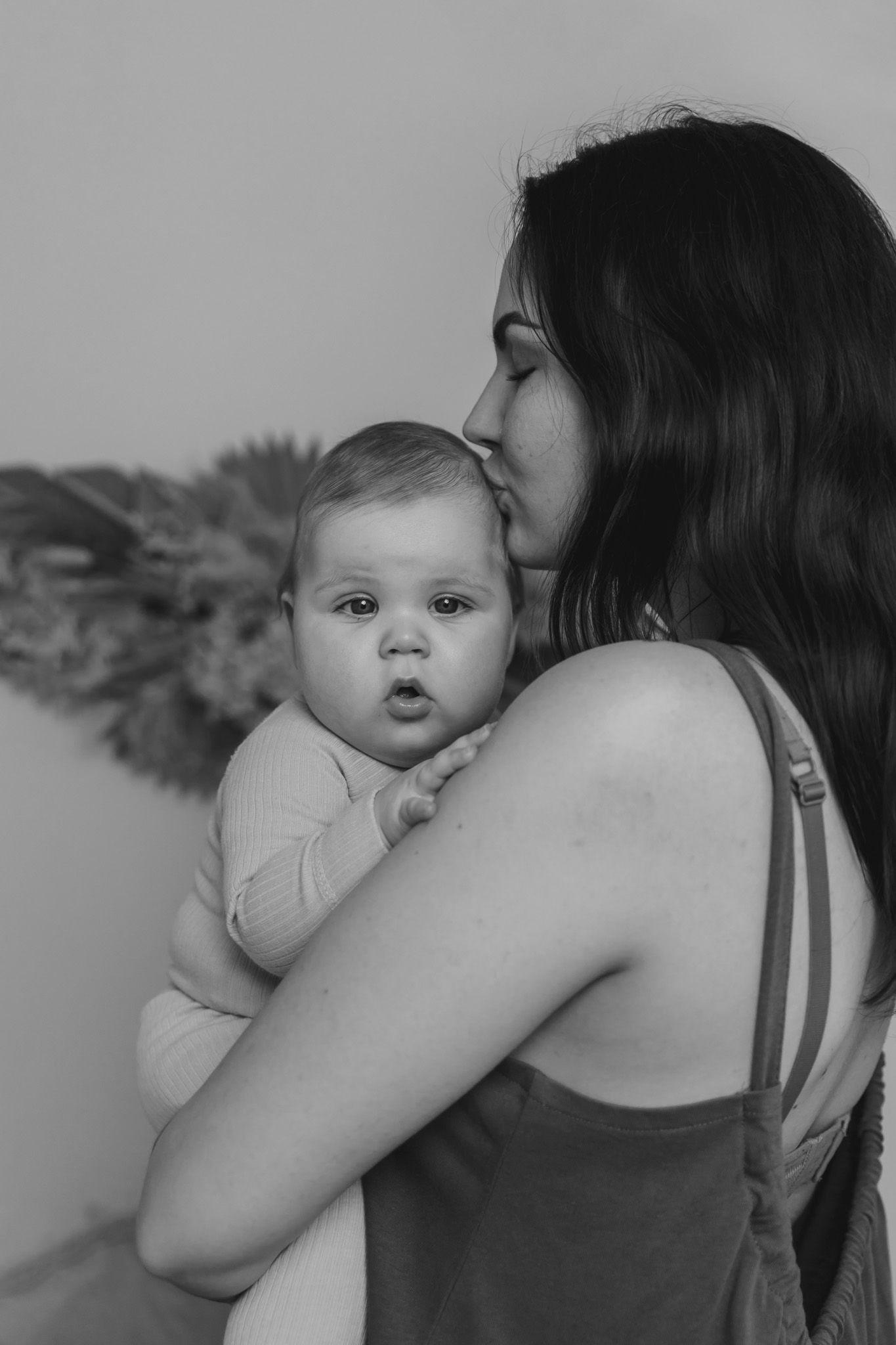 Sort-hvidt portræt af mor, der holder baby i en intim positur. Børnefotograf Fyn
