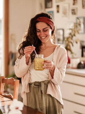 A cozy moment enjoying a healthy drink in a mason jar by a sunlit kitchen window.