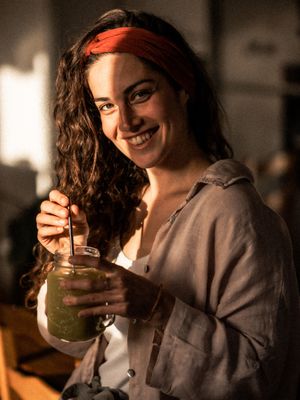 A warm-toned indoor scene showing someone enjoying a refreshing drink from a mason jar.