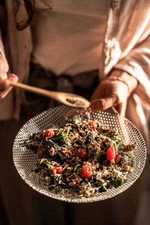 Healthy quinoa salad with cherry tomatoes and greens served on a textured glass plate.