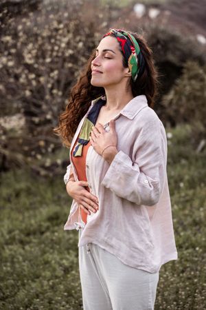 A peaceful outdoor moment in casual attire with a colorful headband against a natural background.