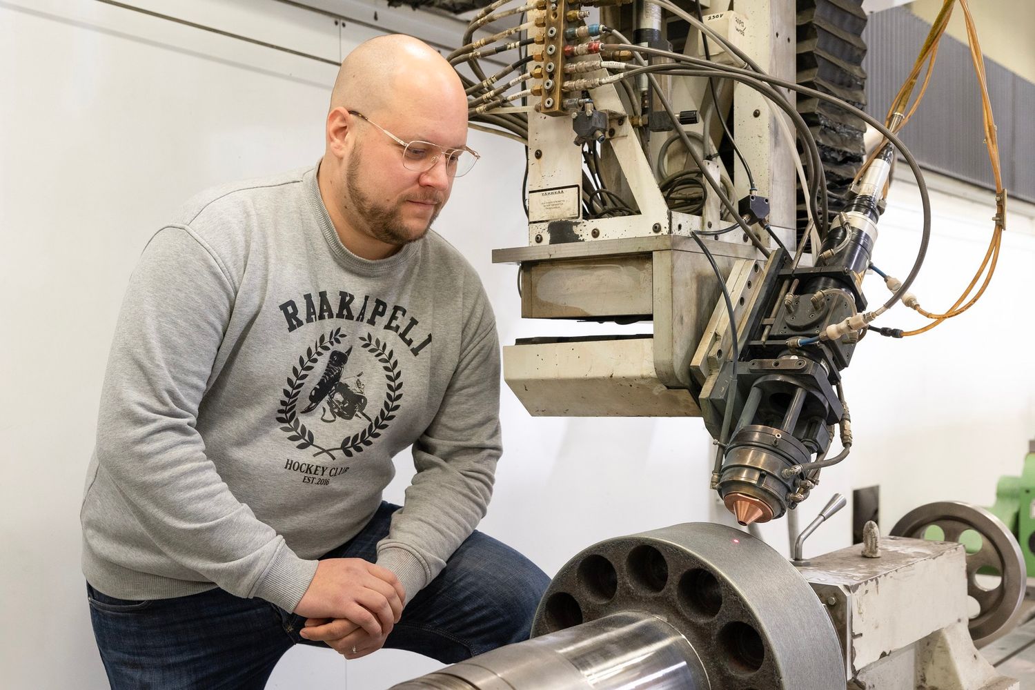 Mies katsoo, kuinka laserkone tekee työtään metalliin.