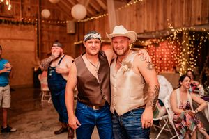 Rustic barn wedding reception with people dancing and celebrating under warm lighting.