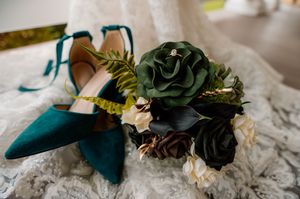 Elegant teal wedding shoes arranged with white and green floral accents.