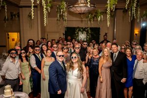 Wedding reception guests gather together for a group photo in a warmly lit venue.