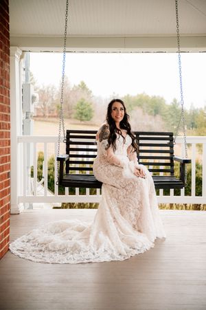 Elegant lace wedding gown displayed on a rustic porch swing in natural lighting.