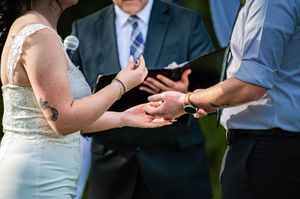 Wedding ceremony in progress with guests seated and couple exchanging vows at the altar.