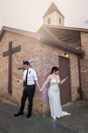 Wedding couple poses against a brick wall for creative outdoor portrait series.