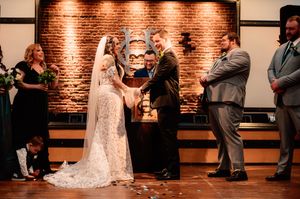 Wedding ceremony taking place in elegant venue with exposed brick walls and warm lighting.