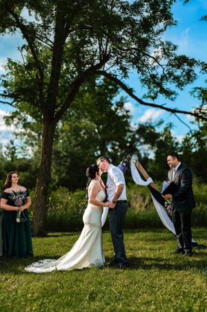 Wedding party takes candid photos on a grassy hill during summer.